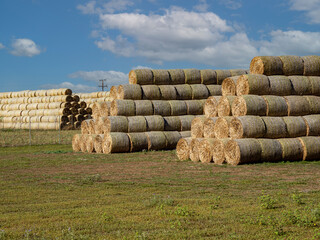 Pyramid of hay barrels stacked in a field near animal farm. Agriculture production concept