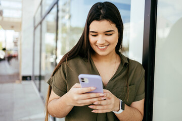 Young hispanic woman wearing casual look smiling confident at the city using smartphone