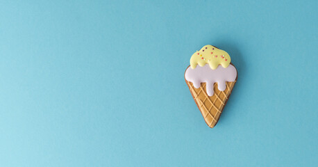 Homemade gingerbread cookie in the shape of ice cream with pastel colors icing. Vintage stylish birthday pastry background. Free space for text. Flat lay with blue background