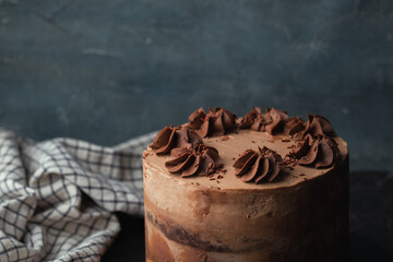 Chocolate sponge cake with brown frosting decorated with chocolate buttercream topping on rustic...