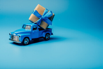 Fototapeta premium The toy car is loaded with a gift. minimalism in blue