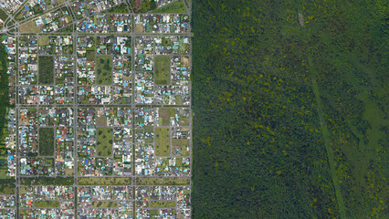 Forest and city border, forest and city separated by straight line, looking down aerial view from...