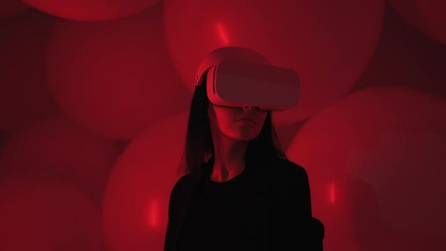 Portrait of attractive woman using VR headset in abstract space with red neon light. Beautiful girl wearing virtual reality glasses in cyberpunk dark atmosphere, concept