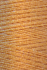 The macro texture of orange cotton thread on bobbin, close-up,