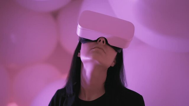 Portrait of young woman using VR metaverse headset in abstract virtual space. Surprised future device female gamer playing videogame at cyberspace background. Modern technologies of digital reality