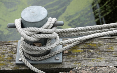 Fototapeta premium Mooring bollard on the quay of a historical harbour in the Netherlands. There is a rope of a ship tied to it.