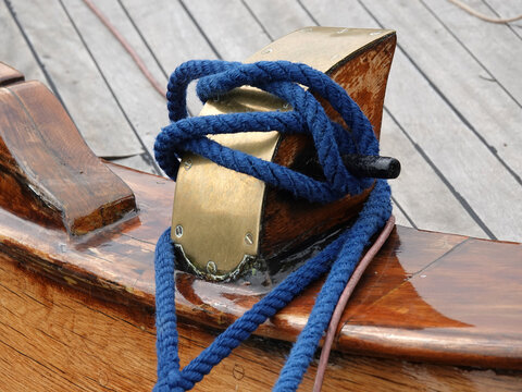 Mooring bollard on the deck of a wooden ship with a blue rope.
