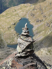 Cairn on a mountain in Andorra with an emerald lake in the background.
