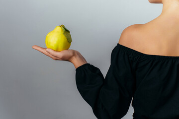 young woman holding a ripe quince fruit in her palm. High quality photo