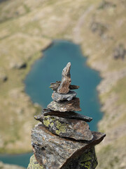 Cairn in close-up on a mountain in Andorra with an emerald lake in the background
