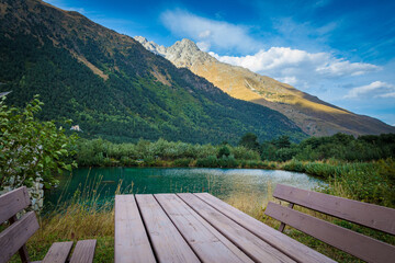 Table with benches against the backdrop of a mountain landscape and a lake. North Ossetia