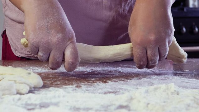 The hands of a Jewish woman forms blanks from dough for baking festive challah. Medium plan