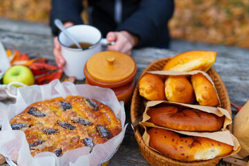 picnic in the autumn season, food on a wooden table, hot tea, pastries and sandwiches