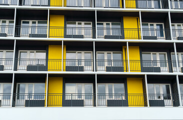 the facade of a modern multi-storey building, windows and balconies, yellow and black walls, the concept of urbanism and city construction