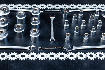 A set of wrenches, hex sockets and gears stacked around the perimeter on a black background.
