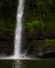 Fototapeta premium beautiful woman takes a bath in a powerful tropical waterfall; waterfall in the middle of the jungle, rainforest waterfall, nandroya falls in atherthone tablelands, queensland, australia