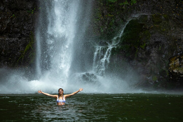 beautiful woman takes a bath in a powerful tropical waterfall; waterfall in the middle of the jungle, rainforest waterfall, nandroya falls in atherthone tablelands, queensland, australia