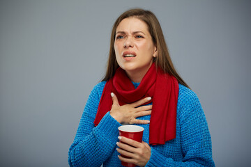 Sick woman with cold fever touching her neck, sore throat, holding red mug. Female person isolated portrait, looking away at side.