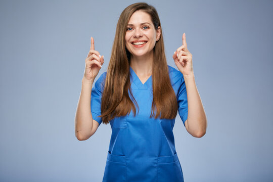 Smiling nurse woman pointing fingers up. Isolated female portrait.