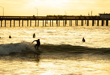 A surfer rides a wave at sunset