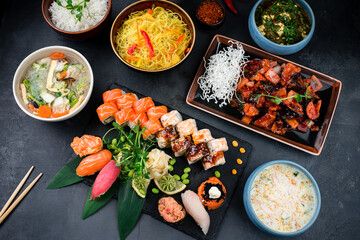 Asian food table with various kind of chinese food, noodles, sour soup, rice, sushi