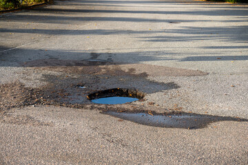 A dep pothole in asphalt parking lot filled with water. © Trygve