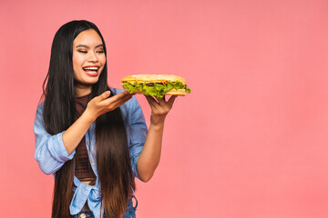 Young beautiful asian japanese chinese woman eating sandwich or big burger with satisfaction. Girl...