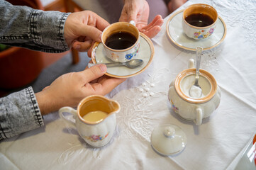 young man offering a cup of coffee to a lady. Using antique coffee set