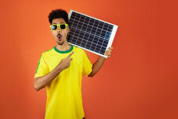 Soccer Player - Black Man Celebrating Holding Solar Photovoltaic Panel Isolated on Orange Background
