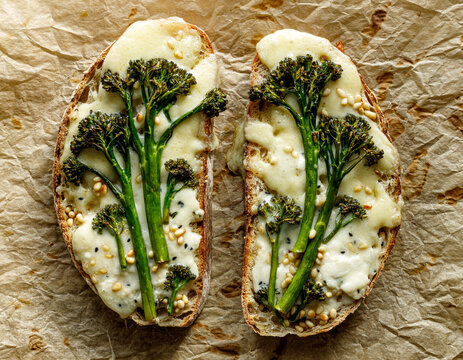 Grilled sandwiches, toasts with addition of baby broccoli, cheese and pine nuts  on parchment paper, top view