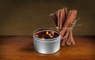 Burning aroma candle and cinnamon sticks
