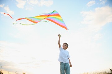 Children launch a kite in the field at sunset.