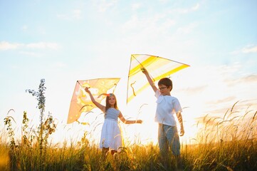 Children launch a kite in the field at sunset