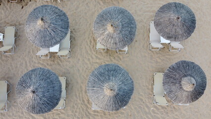 Aerial view of rows of cane umbrellas and sunbeds on a sandy Mediterranean beach