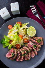 Juicy steak medium rare beef with green salad on plate