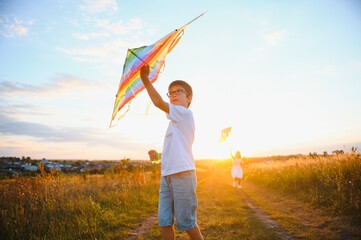 Children launch a kite in the field at sunset