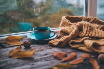 Cup of coffee on a wooden autumn background. Tea and autumn leaves near the window. Coffe on the...