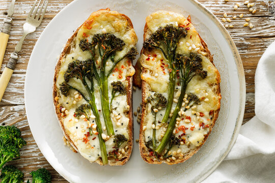 Grilled sandwiches, toasts with baby broccoli, cheese and pine nuts on a plate, top view