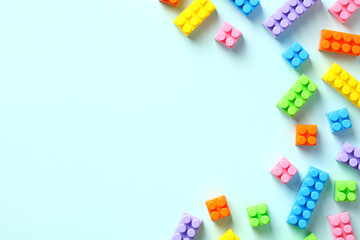 Colorful plastic building blocks on pastel blue background. Flat lay, top view, copy space....