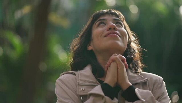 Spiritual woman feeling grateful praying looking at sky smiling. Person having HOPE and FAITH in prayer. GRACE concept