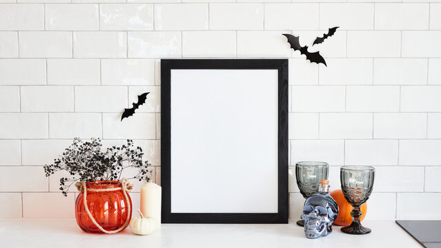Black frame mockup and spooky halloween home decor on desk table in scandinavian kitchen interior. Halloween holiday concept.