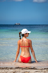 Fototapeta premium Brunette woman with coral bikini and cap posing on the beach
