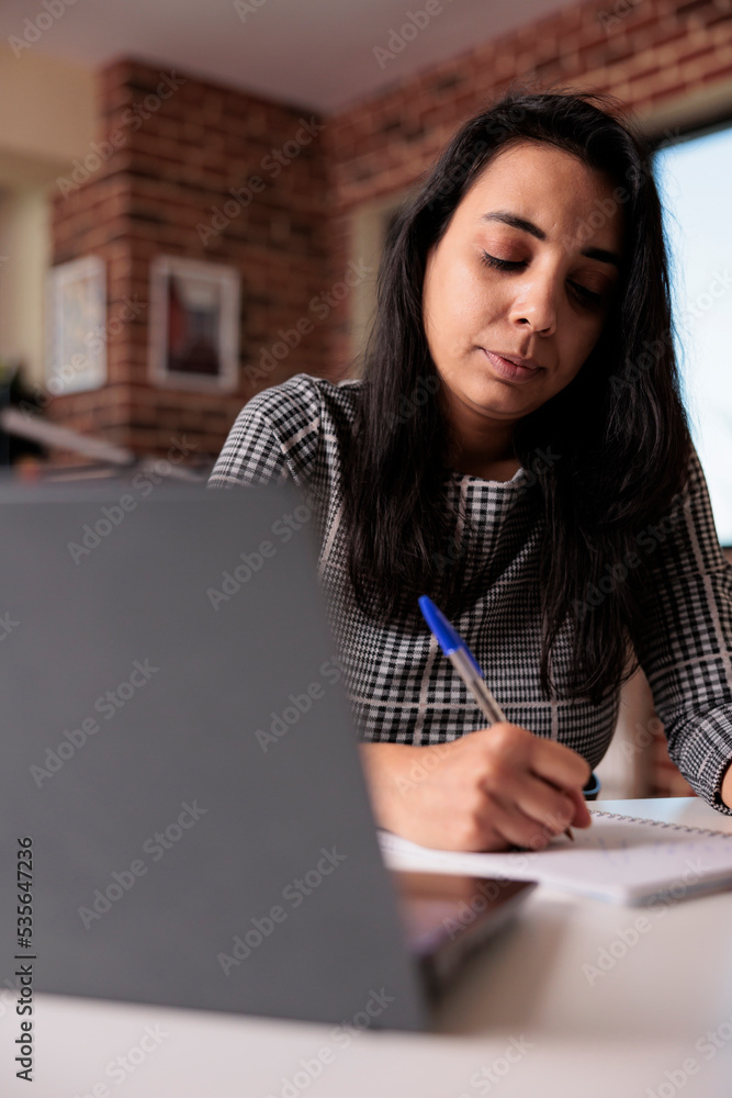 Poster freelancer writing report on notebook, doing remote job from home and taking notes about startup kno