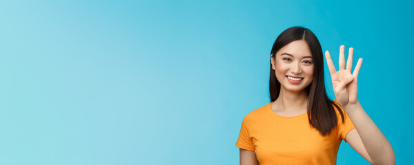 Fototapeta na wymiar Close-up charismatic tender stylish asian female show number four fingers, smiling happily, making order, explain how much items want buy, stand blue background carefree