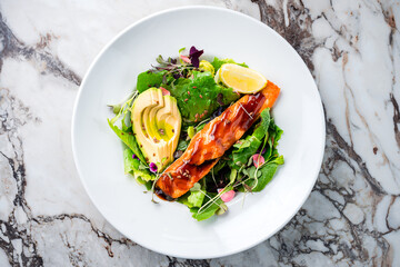 Oven cooked salmon steak, fillet with avocado salsa and green on plate healthy food