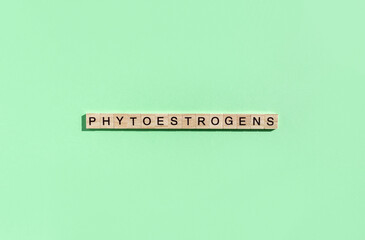 Word Phytoestogen made from letters on wooden blocks on green background. Alternative methods of hormonal therapy in menopause. Сopy space