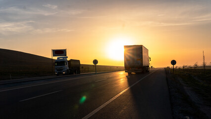 Naklejka na ściany i meble View of trucks carrying loads at sunrise