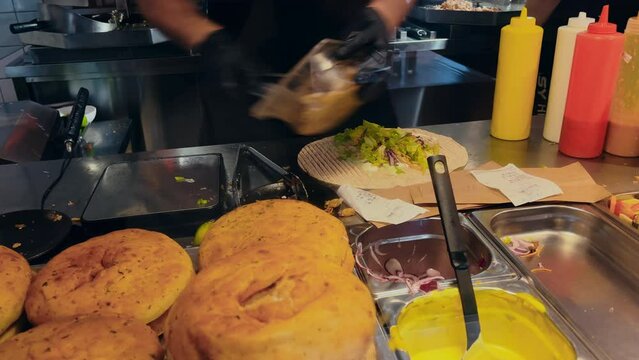 Very fast and urgent man is cooking a kebab or wrap in an undergroung european cafe
