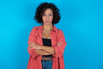 Picture of angry young beautiful woman with curly short hair wearing red overshirt looking camera. - obrazy, fototapety, plakaty
