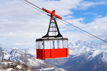 Red retro cable car cabin against the backdrop of snow-capped mountains